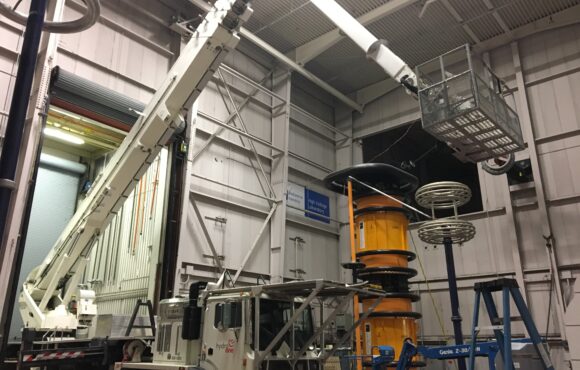 A bucket truck deployed indoors within a large testing facility