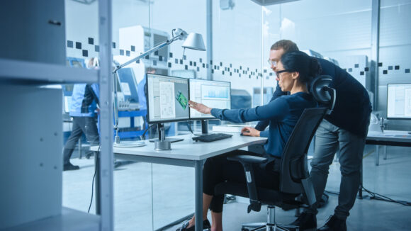 Workers in a lab examining 3d model on a computer