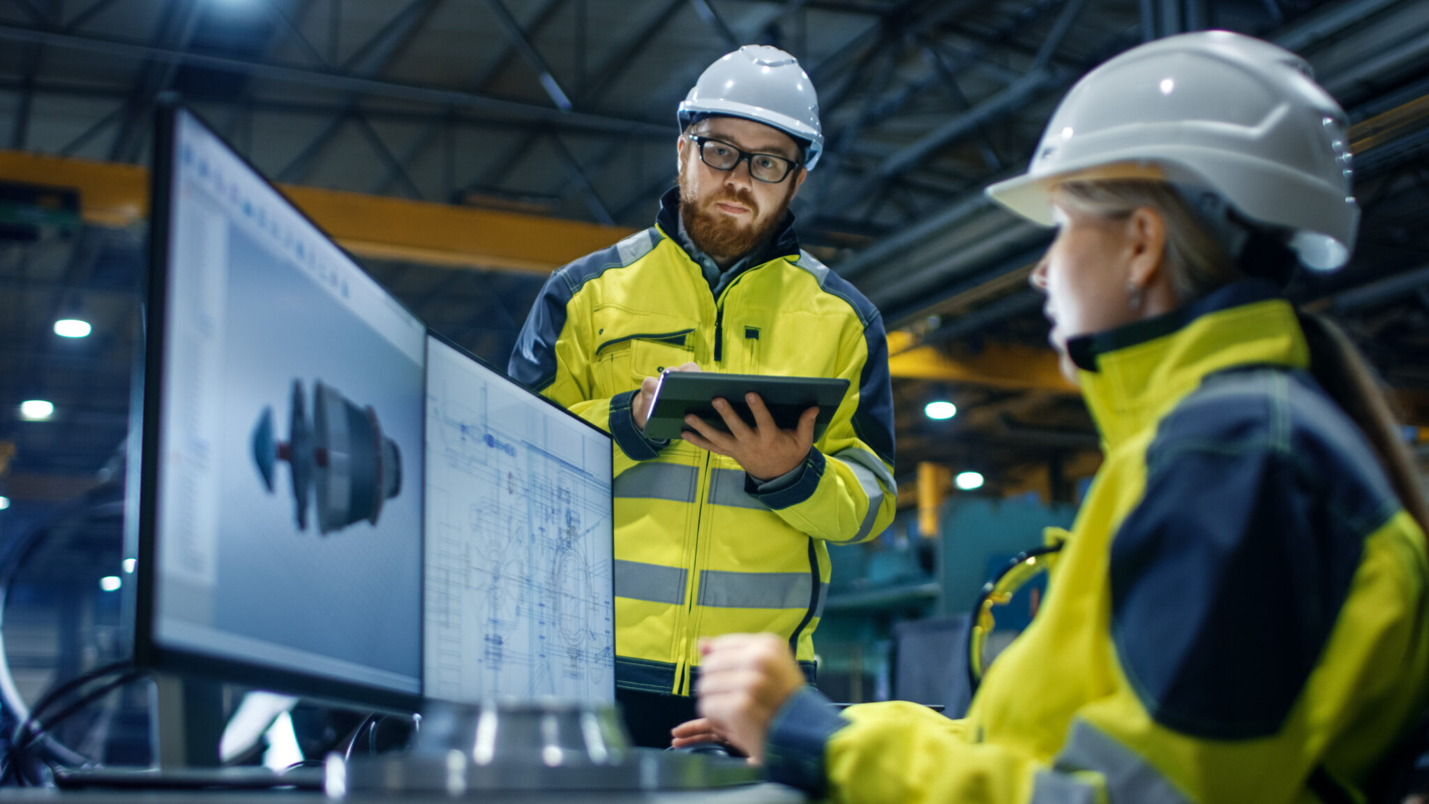 Engineers in hardhats and hiviz jackets studying a design drawing