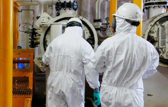 Workers wearing white protective suits in nuclear facility