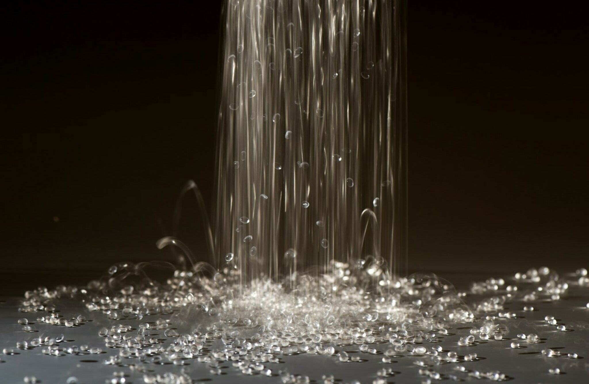 Glass beads cascading onto a flat gray surface.