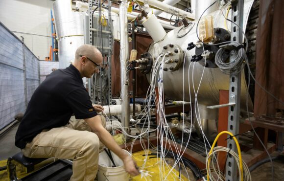 Worker attaching monitoring equipment to a large nuclear component