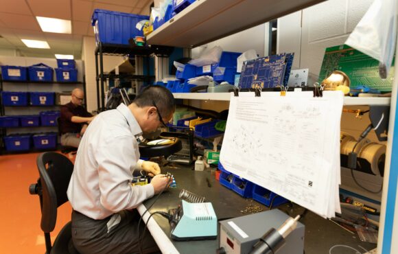 Worker soldering parts onto a reverse engineered circuit board