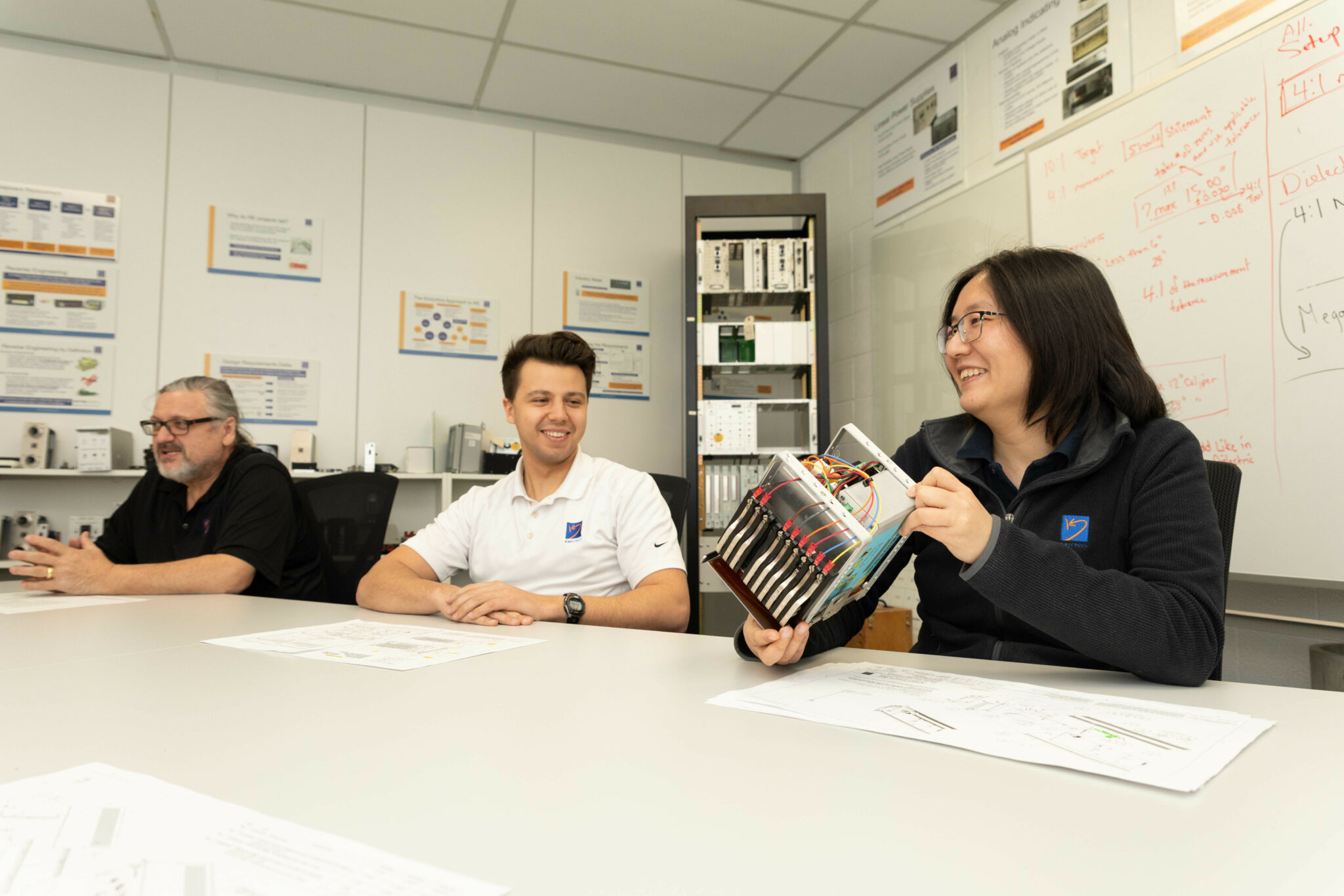 Workers in a boardroom discussing a component that they are reverse engineering