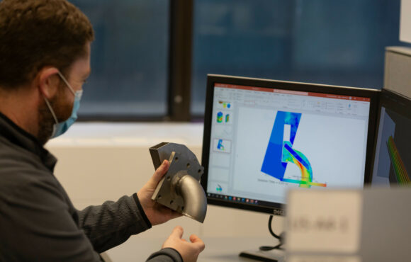 Worker comparing physical piece of piping to a computer-generated 3d model
