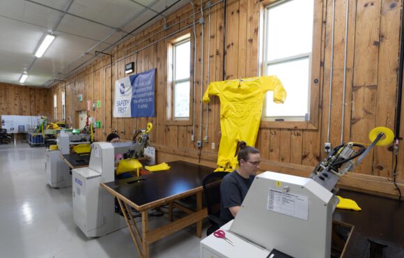 Assembly workers constructing protective suits at work tables