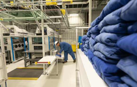 Worker inspecting line of folded uniforms