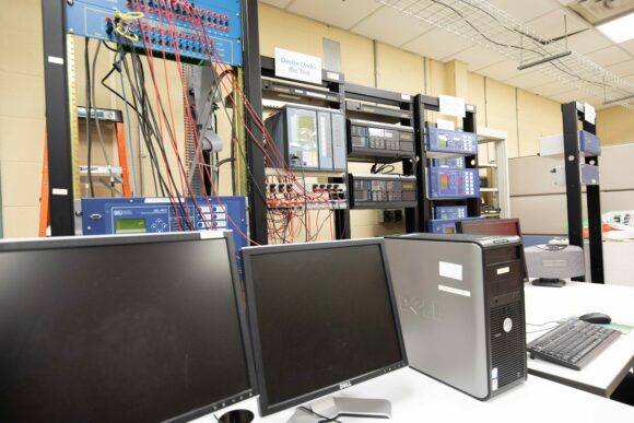 Computer monitors in front of rack mounted testing equipment