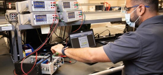 A worker testing machine parts at a work bench
