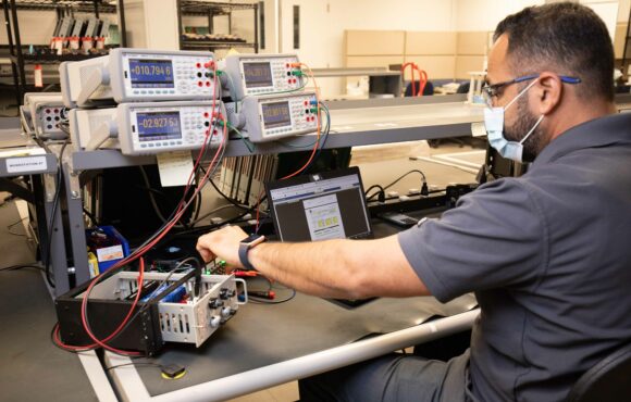A worker testing machine parts at a work bench