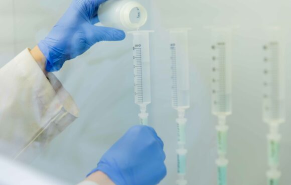 Closeup photograph of worker filling test tube with liquid