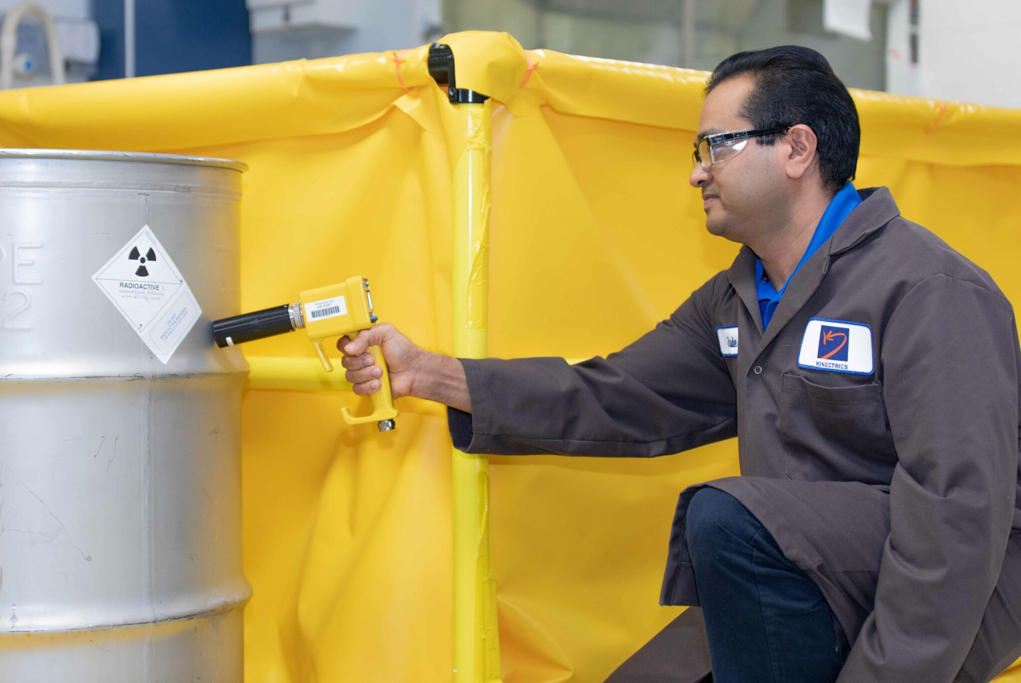 Radiation technician scanning a container filled with radioactive waste material