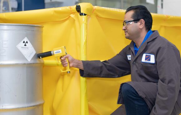 Radiation technician scanning a container filled with radioactive waste material