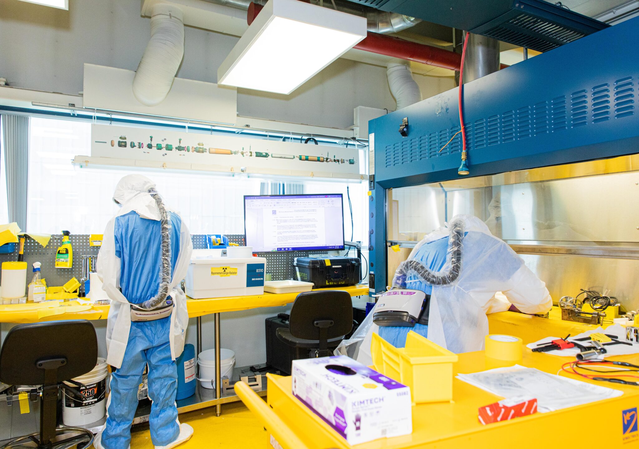 Workers in protective suits working on contaminated components in a radioactive lab