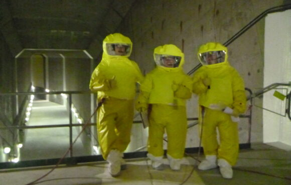 Workers in protective suits walking through nuclear facility