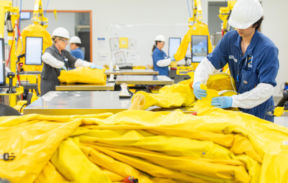 Workers inspecting line of folded protective suits