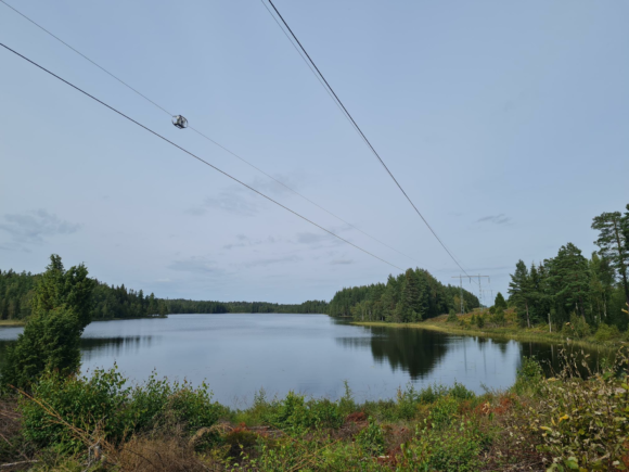 Outdoor photograph of LineVue unit performing testing on a transmission cable suspended over a small lake